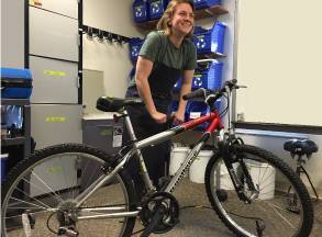 female student inflating bike tire with hand pump
